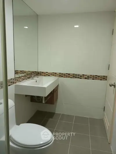 Modern bathroom with sleek design and stylish tile accents, featuring a wall-mounted sink and contemporary fixtures.