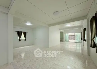 Spacious open-plan living area with tiled flooring and large windows for natural light.