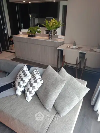Modern living room with stylish grey sofa and open kitchen layout