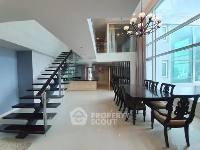 Luxurious open-plan dining area with elegant staircase and large windows in modern apartment.