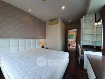 Spacious bedroom with modern decor and view into cozy living room