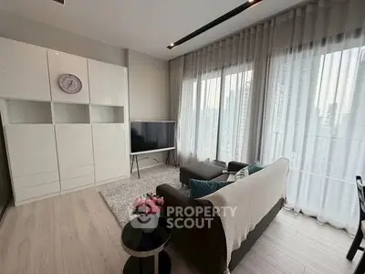 Modern living room with sleek furniture and large windows offering city views.