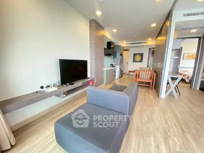 Modern open-plan living room with sleek furniture and wooden flooring in a stylish apartment.