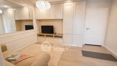 Elegant living room with built-in cabinets and cozy seating area, featuring a stylish chandelier and modern decor.