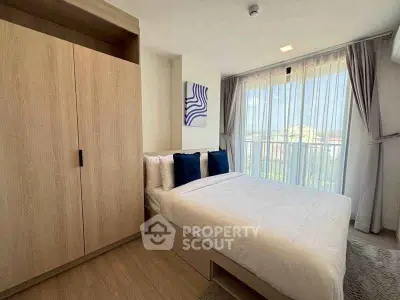 Modern bedroom with large window and stylish decor in a high-rise apartment.