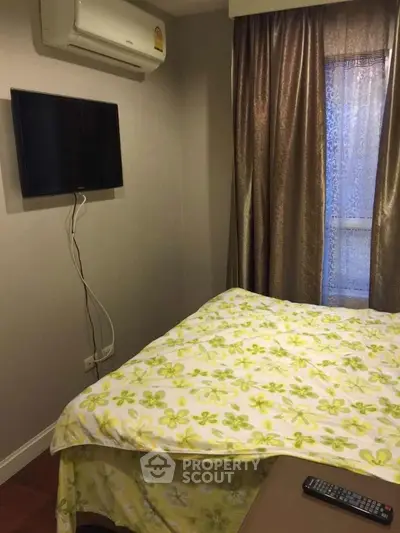 Cozy bedroom with wall-mounted TV and air conditioning, featuring floral bedding and elegant curtains.