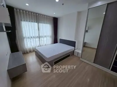 Spacious modern bedroom with large window and mirrored wardrobe