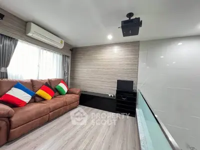 Modern living room with cozy brown sofa and colorful pillows, featuring a projector and sleek decor.