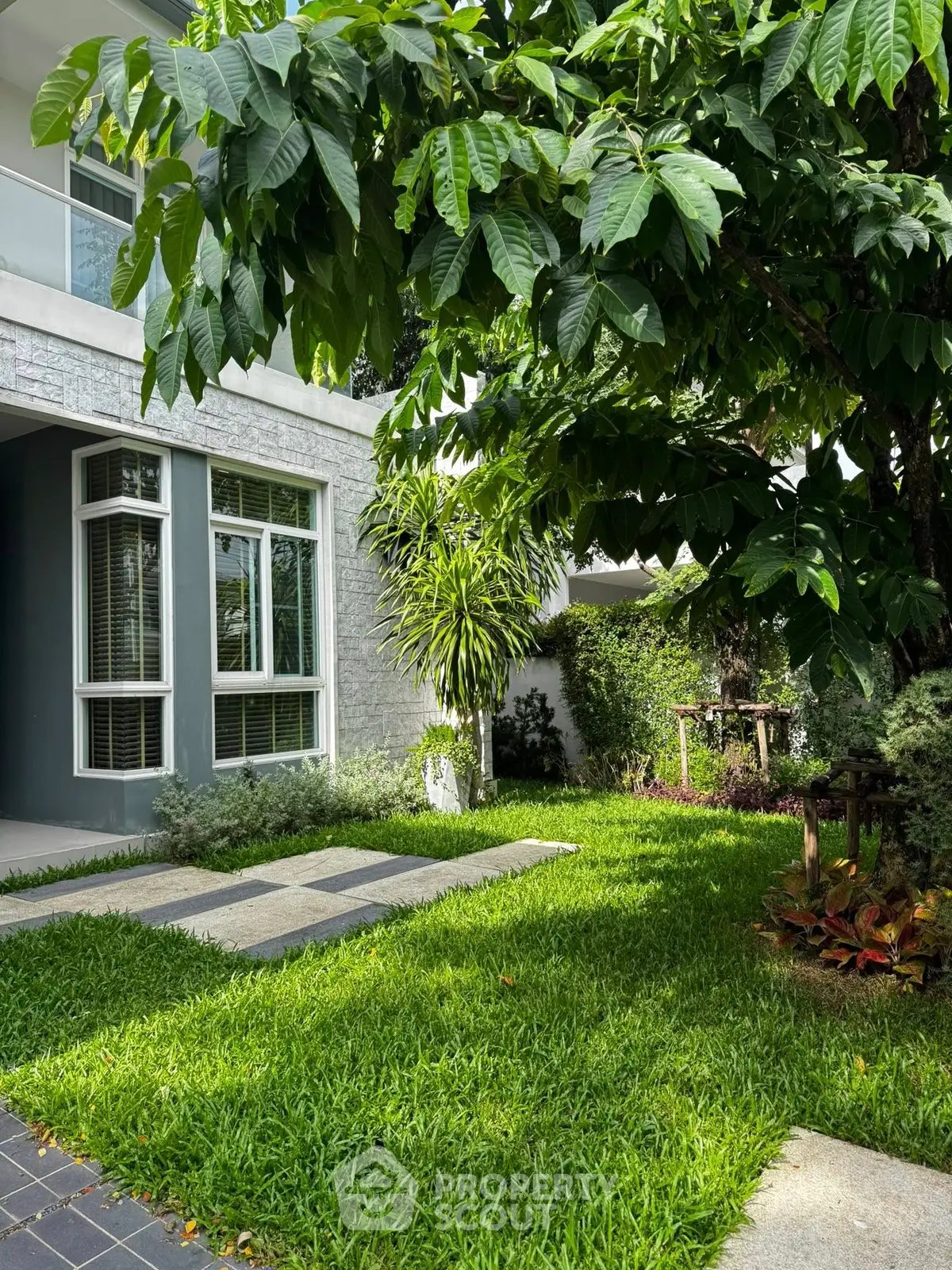 Charming modern home exterior with lush green garden and large windows, perfect for nature lovers.