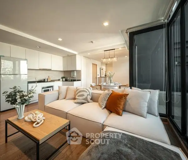 Spacious open-plan living room seamlessly connected to a modern kitchen, featuring plush seating, elegant decor, and ample natural light.