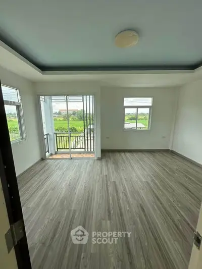 Spacious room with large windows and balcony overlooking greenery, perfect for modern living.