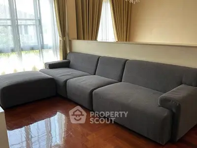 Spacious living room with modern gray sectional sofa and large windows.