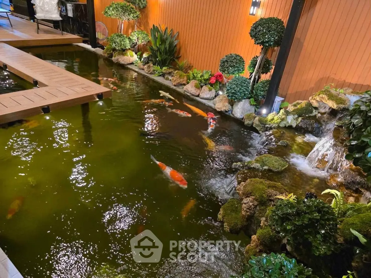 Stunning koi pond with lush greenery and wooden bridge in serene garden setting.