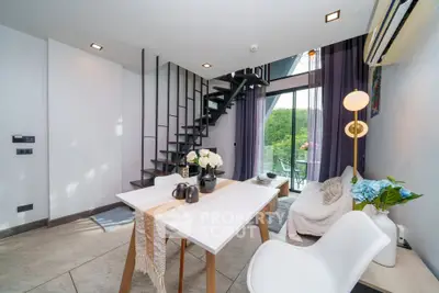 Modern duplex living room with stylish decor and large windows offering lush green views.