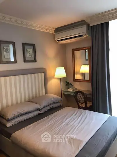 Cozy bedroom with elegant decor, featuring a comfortable bed, stylish lamp, and air conditioning for ultimate comfort.