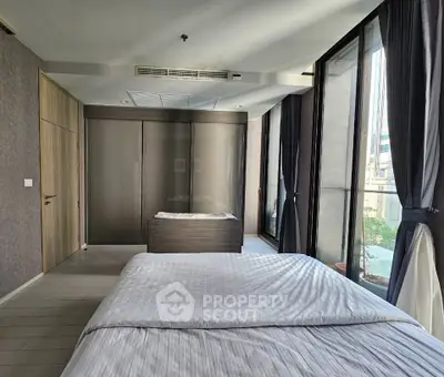 Spacious bedroom with large windows and modern decor in a luxury apartment.