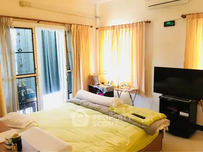 Cozy bedroom with natural light, featuring a comfortable bed, TV, and access to a private balcony.