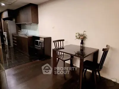 Modern kitchen with dark wood cabinets and dining area in sleek apartment