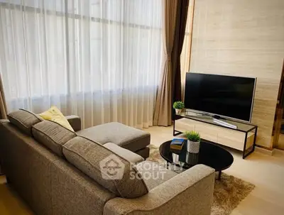 Modern living room with large windows, cozy sofa, and sleek TV setup.
