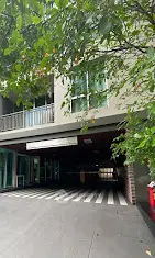 Modern building entrance with lush greenery and spacious driveway