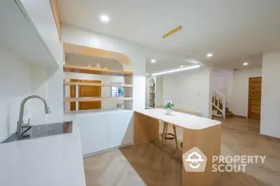 Modern kitchen with sleek design and open layout, featuring wooden accents and bright lighting.