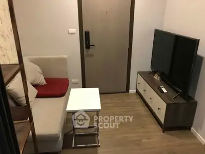 Cozy living room with modern TV setup and comfortable seating in a compact apartment.