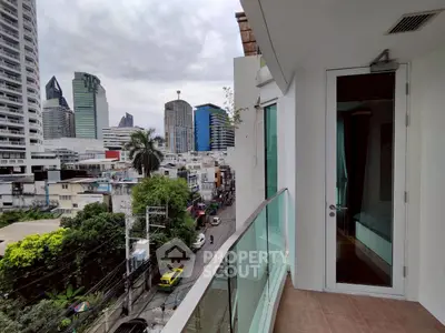 Modern city view from a stylish balcony with glass railing in a high-rise building.