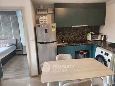 Modern kitchen with sleek appliances and dining area, adjacent to a cozy bedroom.
