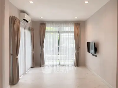 Spacious modern living room with large windows and elegant curtains