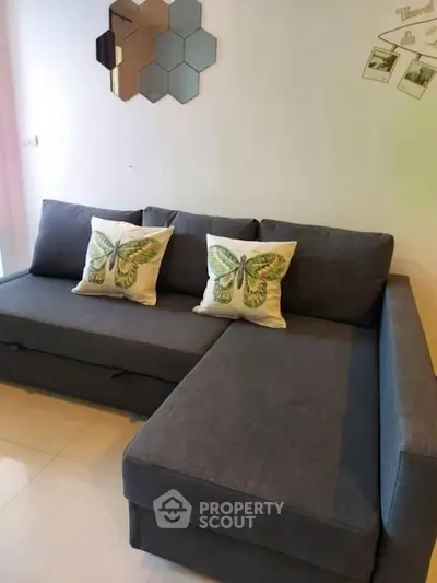 Modern living room with stylish gray sectional sofa and butterfly-themed cushions.
