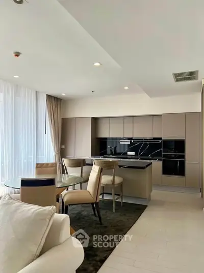 Modern open-layout kitchen with dining area and sleek cabinetry in a bright apartment.