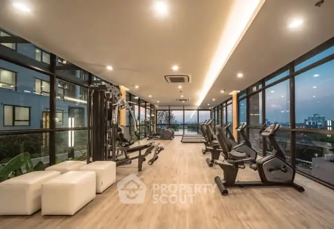 Luxurious gym with modern equipment and panoramic city views in upscale residential building.