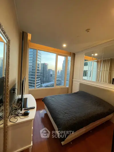 Luxurious bedroom with stunning city view and elegant decor in high-rise apartment.