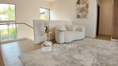 Elegant modern living room with plush white sofa and abstract art, featuring large windows and natural light.