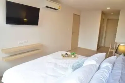 Modern bedroom with wall-mounted TV and air conditioning in a stylish apartment.
