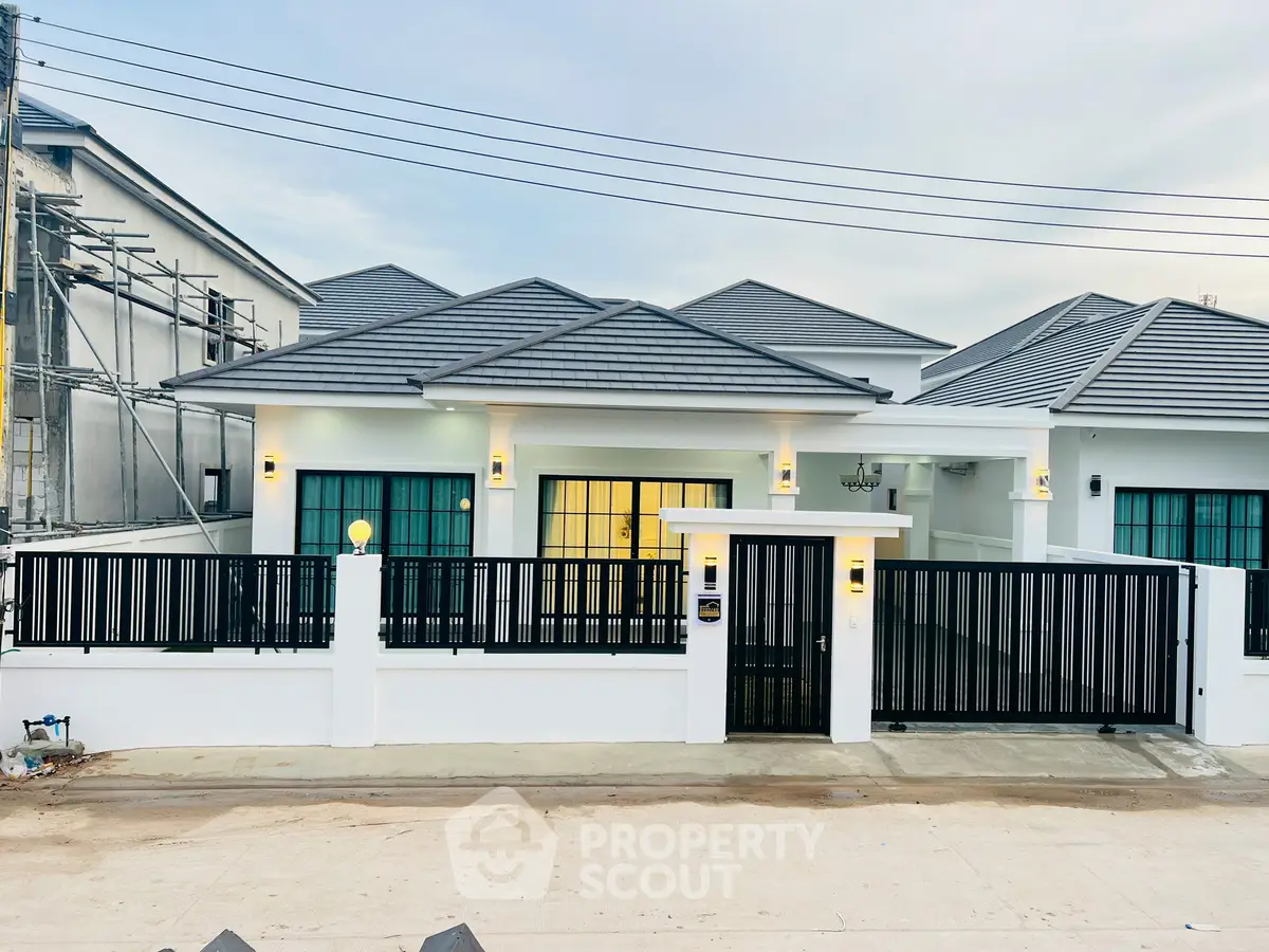 Modern single-story house with sleek black fence and contemporary roof design.