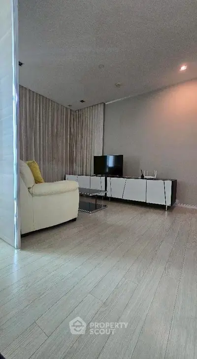 Modern living room with sleek furniture and TV setup, featuring elegant flooring and neutral tones.