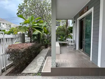 Charming patio with lush garden view and cozy seating area in modern home exterior.