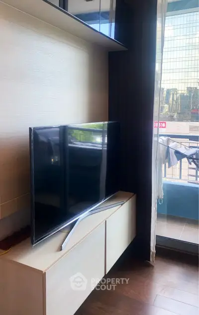 Modern living room with sleek TV and balcony view in high-rise apartment