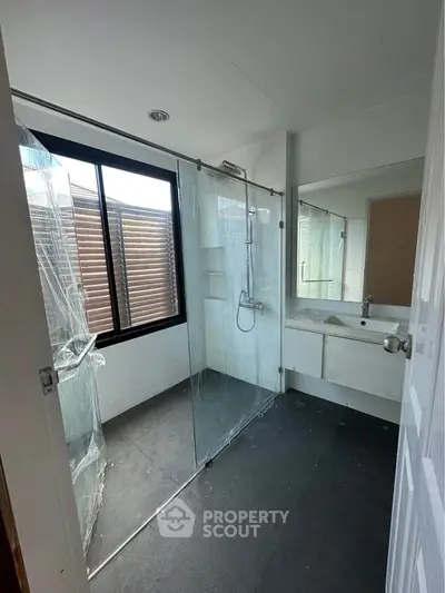 Modern bathroom with glass shower enclosure and large window for natural light.