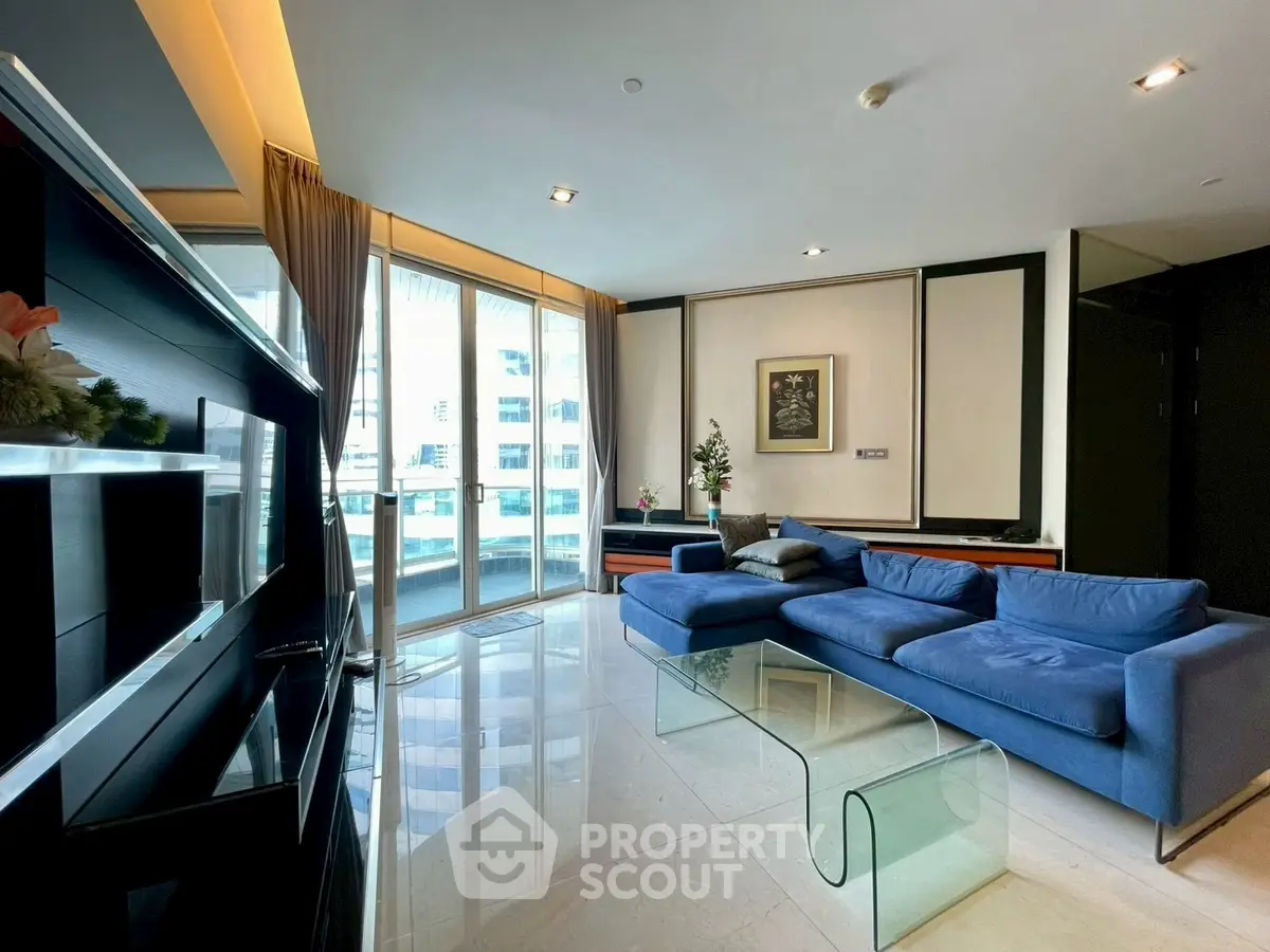 Luxurious living room with modern blue sofa and glass table, featuring floor-to-ceiling windows and elegant decor.