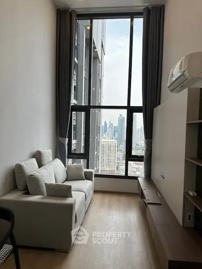 Modern living room with large window offering stunning city view in high-rise apartment.