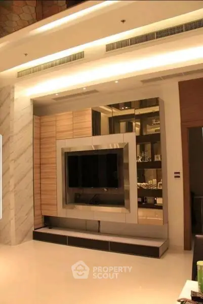 Luxurious modern living room with built-in entertainment center and elegant lighting.