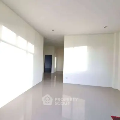 Spacious empty room with glossy floor and large windows for natural light.