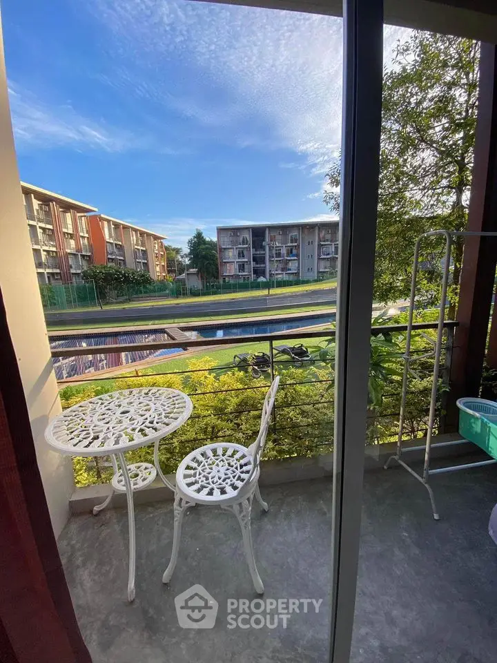 Charming balcony view with elegant outdoor furniture overlooking lush greenery and modern apartments.