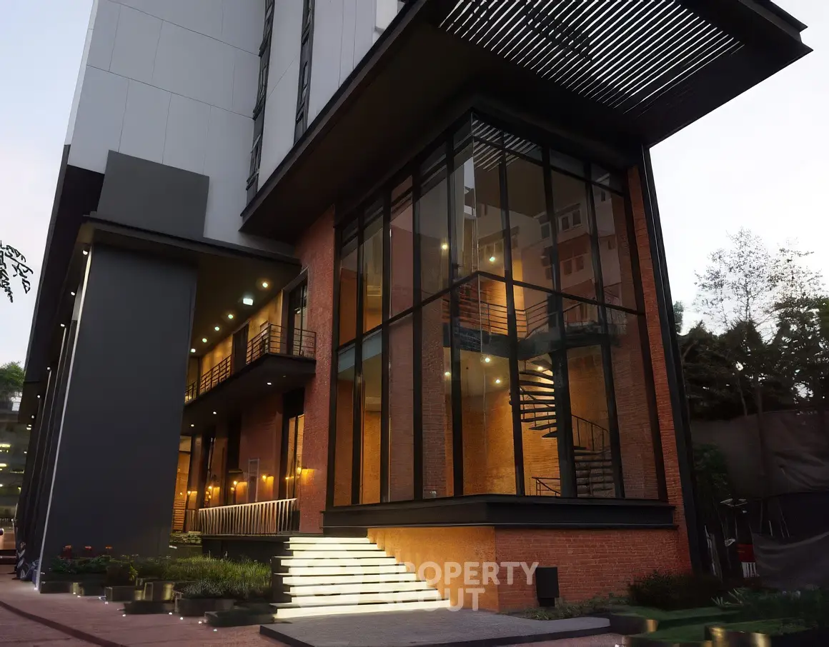 Modern building exterior with large glass windows and illuminated entrance steps.