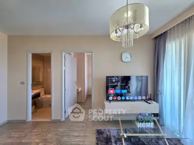 Modern living room with TV, chandelier, and stylish decor in a cozy apartment.