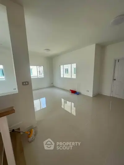 Spacious empty room with glossy tiled floor and large windows, perfect for customization.