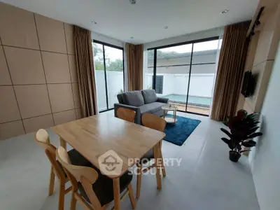 Modern living room with pool view, stylish furniture, and natural light