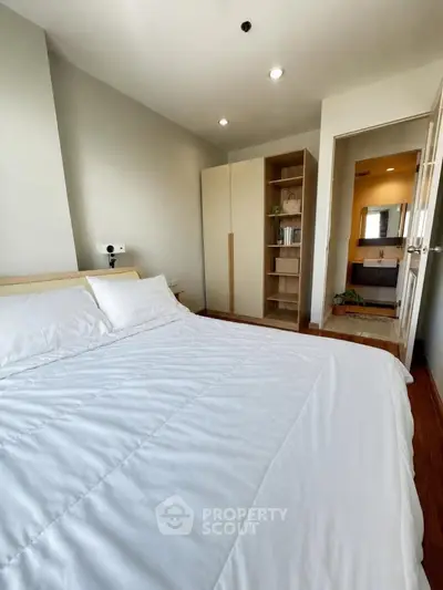 Cozy bedroom with modern decor and ensuite bathroom, featuring a comfortable bed and ample storage space.
